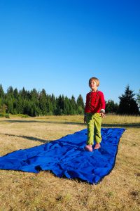 girl imitating photo-model on on blue carpet in nature